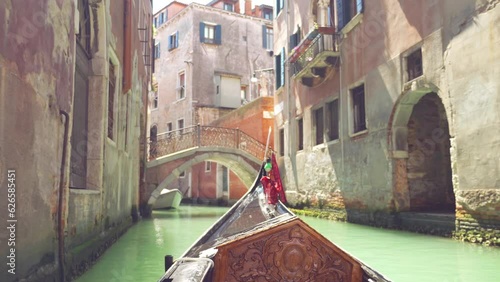 View from the front of the gondola of Venice canals, moored boats and architecture of the city during ride along one of the canals in Venice, Italy.