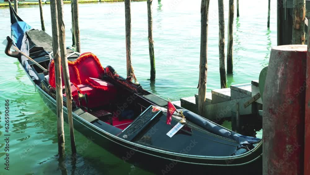 Gondola moored with palines at the ferry pier near the waterfront at the Riva degli Schiavoni, in Venice, Italy. Gondola moored with palines at the ferry pier near the waterfront at the Riva degli Schiavoni, in Venice, Italy.