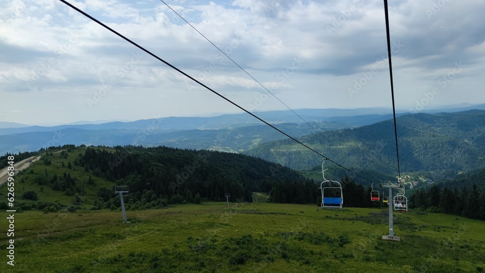 Ski resort, with green mountainside in summer and lift chairs through the forest with ropes on top