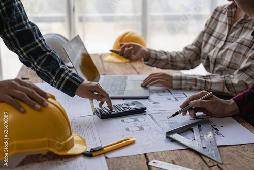 Engineers point to buildings on blueprints and use building design laptops, construction projects of engineers who work on drawings in blueprint meetings for projects, work with modeling partners.