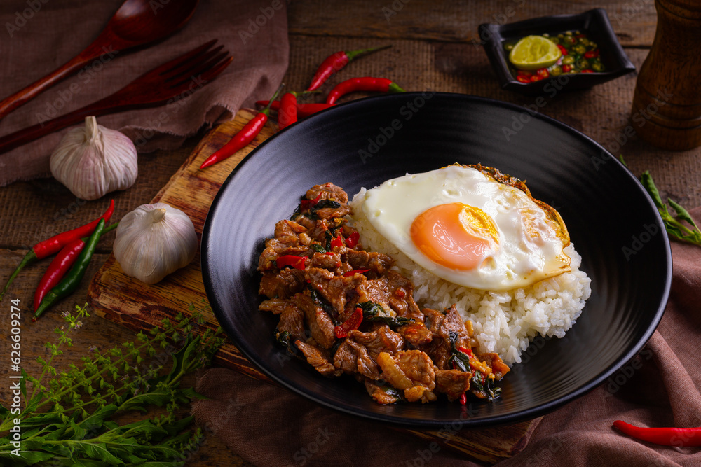 Stir fried sliced Beef with Holy Basil and Cooked Rice topped with fried egg in black plate.Thai spicy food(Pad Kra pao)