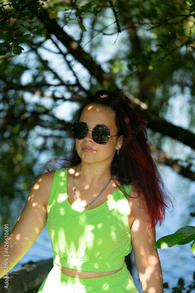 Portrait of a girl in sunglasses near the river in a city park in summer Portrait of a girl in sunglasses near the river in a city park in summer