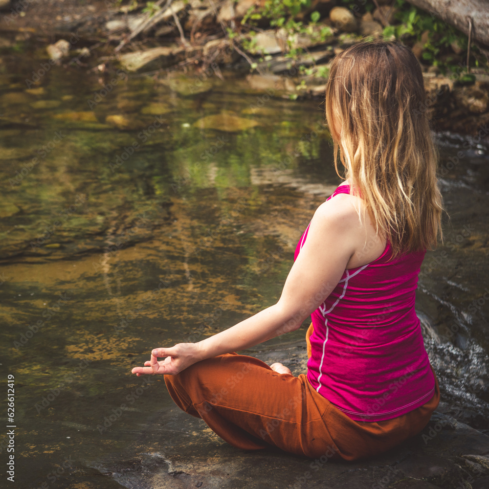Woman doing yoga on the stone at the mountain river. Carpathians Woman doing yoga on the stone at the mountain river. Carpathians