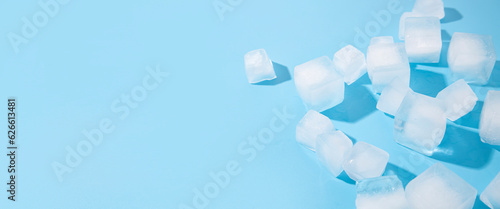 Many ice cubes on a blue background. Top view, flat lay. Banner photo
