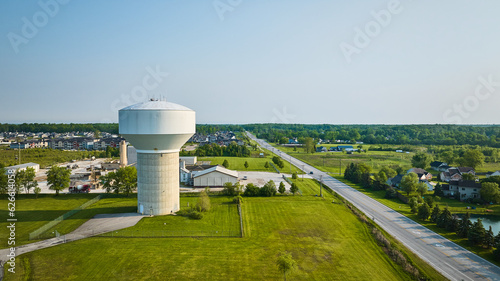 Billede på lærred Nondescript white water tower with nearby housing rural area aerial