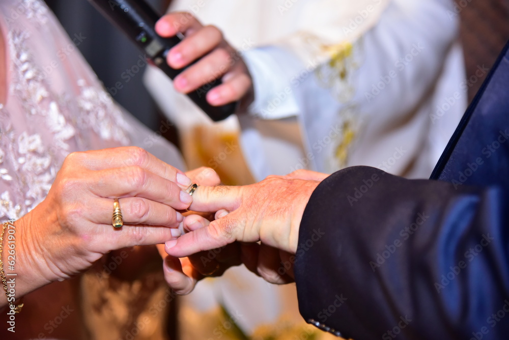 Fototapeta premium bride and groom holding hands, bride and groom hands putting on wedding rings close-up
