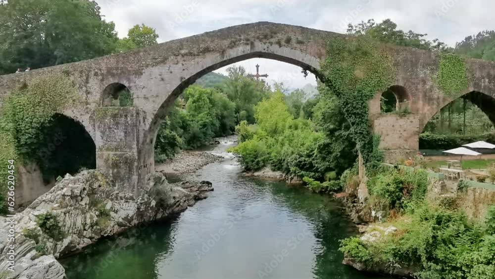 Panoramic view at the Roman bridge over Sella river, an iconic bridge on Cangas de Onís downtown city, Picos de Europa or Peaks of Europe, Cantabrian Mountains, Spain Panoramic view at the Roman bridge over Sella river, an iconic bridge on Cangas de Onís downtown city, Picos de Europa or Peaks of Europe, Cantabrian Mountains, Spain