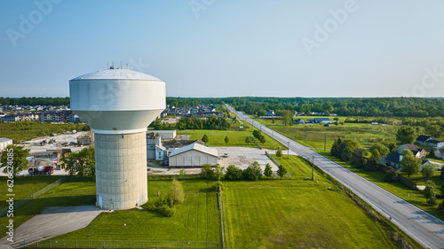 Rural area aerial nondescript white water tower with nearby housing photo