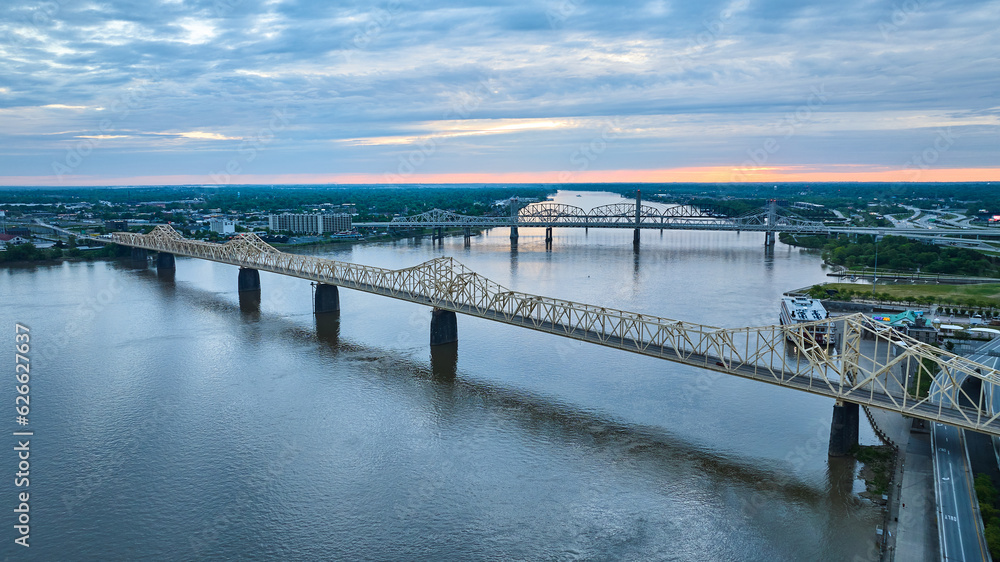 Pink sunset glow on horizon aerial over Ohio River water truss bridges