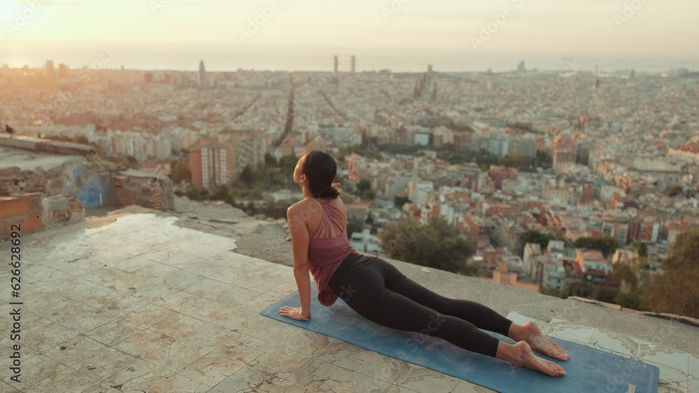 Girl practices handstand yoga asana at lookout point at dawn
