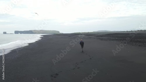 Lonely manwalking  on the beach of Iceland, Reynisdrangar, aerial photo