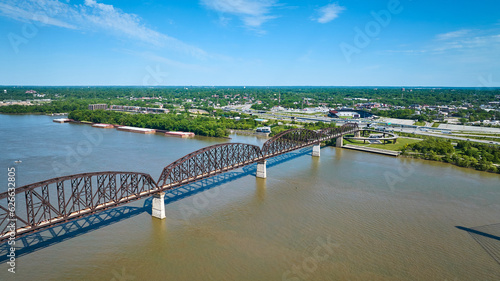 Aerial iron arch bridge over Ohio River water murky distant city blue sky