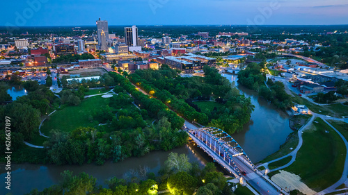 Wide view aerial downtown Fort Wayne at dusk with lights on bridge and buildings photo