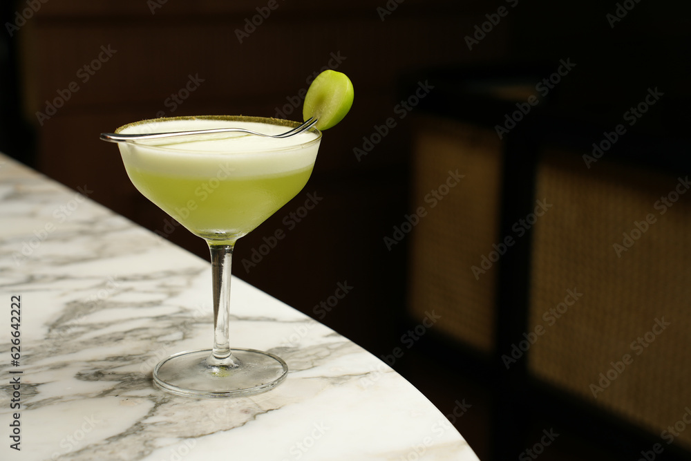 Green cocktail glass on a marble bar counter