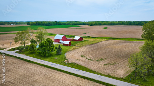 Property farm farmhouse barn and shed green pasture empty plowed fields with paved road aerial