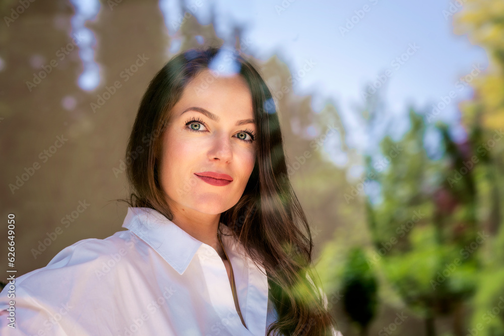Beautiful young woman with brunette hair and blue eyes standing behind the window Beautiful young woman with brunette hair and blue eyes standing behind the window