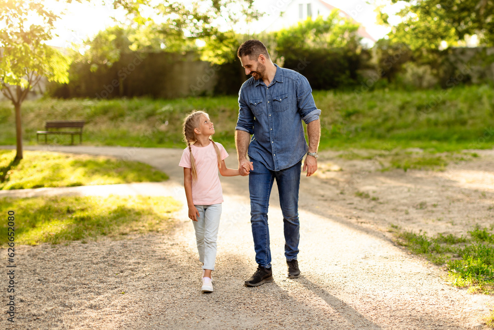 Happy family dad and daughter holding hands while walking in park, dad spending free time with his beloved child Happy family dad and daughter holding hands while walking in park, dad spending free time with his beloved child