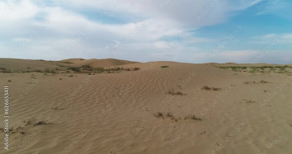Drone flies very low over the desert sand dunes, kicking up dust with its propellers Drone flies very low over the desert sand dunes, kicking up dust with its propellers