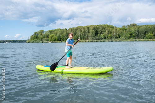 A 10-year-old boy rides a SUP board on a river or lake alone photo