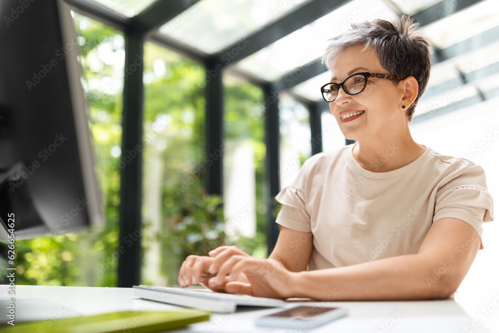 Happy mature woman remote working from home office on pc Happy mature woman remote working from home office on pc