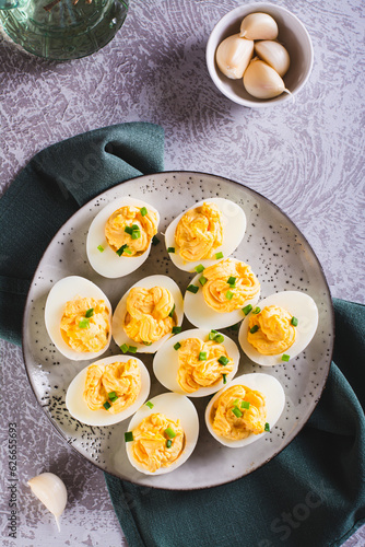 Boiled eggs stuffed with yolk, cheese, garlic and mayonnaise on a plate top and vertical view