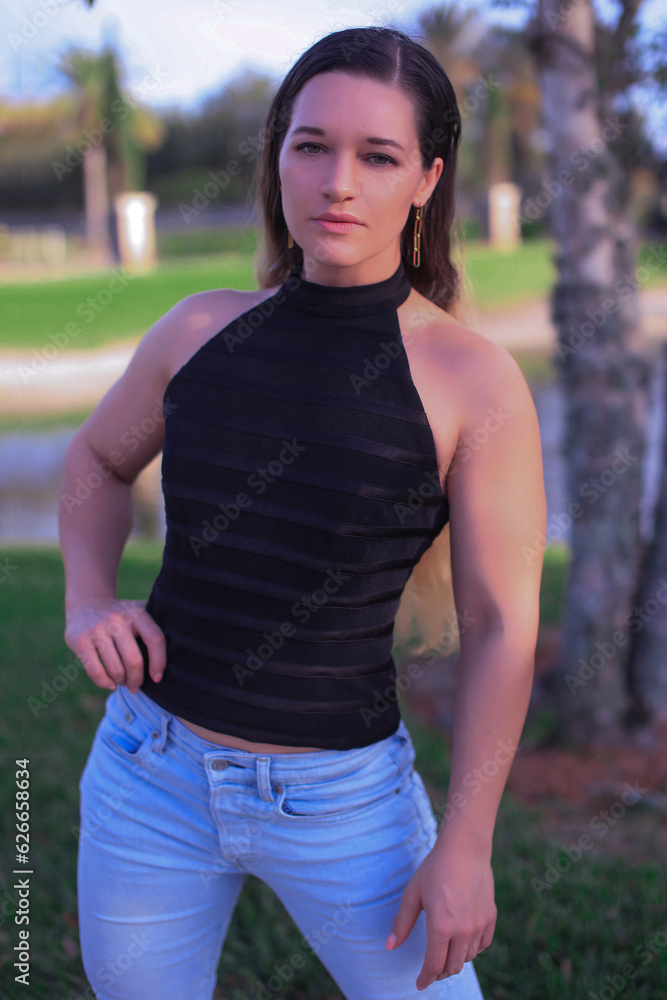 a beautiful big athlete fitness girl in a black top and jeans poses on the street of America, in summer and smiles a beautiful big athlete fitness girl in a black top and jeans poses on the street of America, in summer and smiles