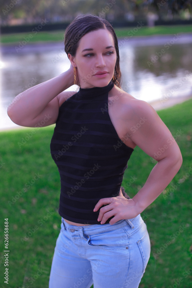 a beautiful big athlete fitness girl in a black top and jeans poses on the street of America, in summer and smiles a beautiful big athlete fitness girl in a black top and jeans poses on the street of America, in summer and smiles