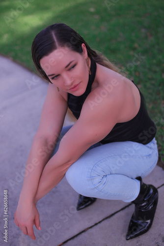 a beautiful big athlete fitness girl in a black top and jeans poses on the street of America, in summer and smiles