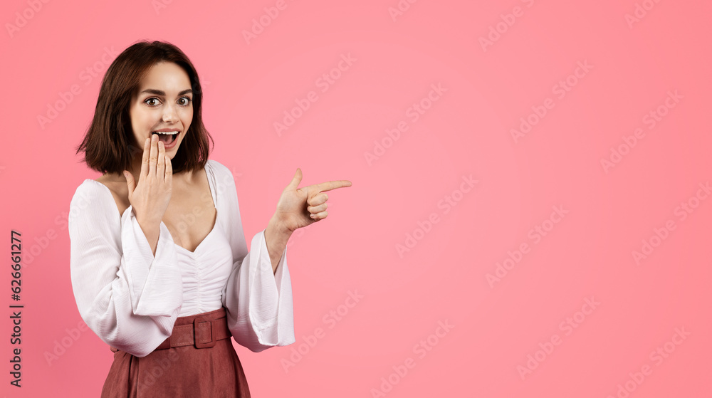Glad shocked millennial caucasian brunette woman with open mouth pointing finger at free space Glad shocked millennial caucasian brunette woman with open mouth pointing finger at free space
