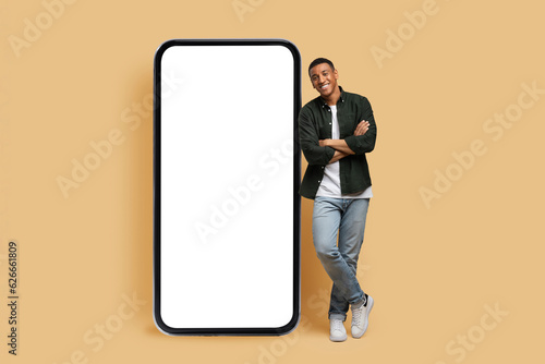 Happy young black man posing by phone with white screen