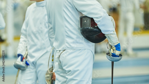 body parts of the athlete fencing in a suit uniform with a sword and mask. An active Olympic sport.