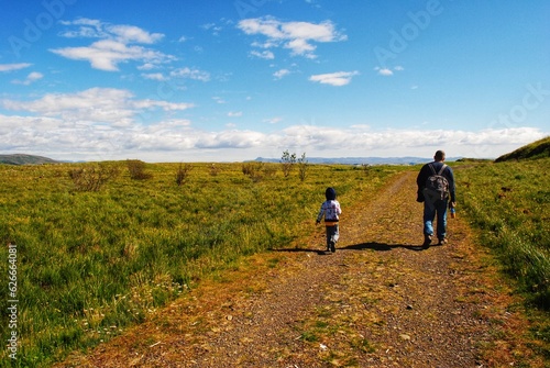 A father and son walk on a trail in Videy Island, Iceland.