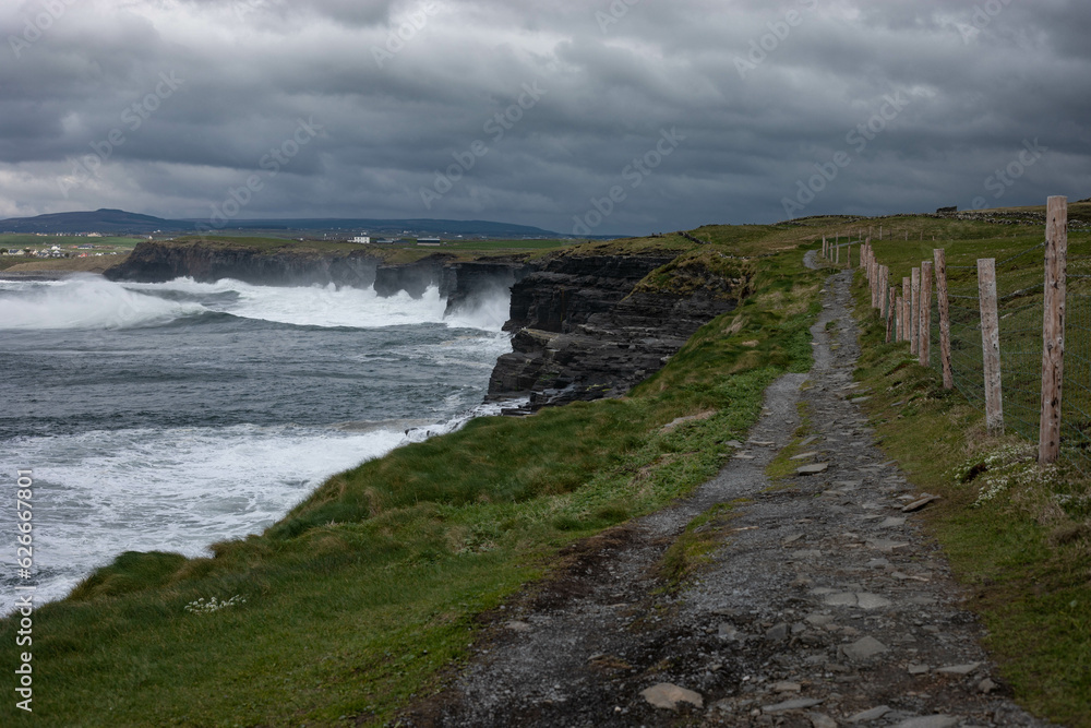 scenery of cliff walk path with rough ocean on a cloudy day