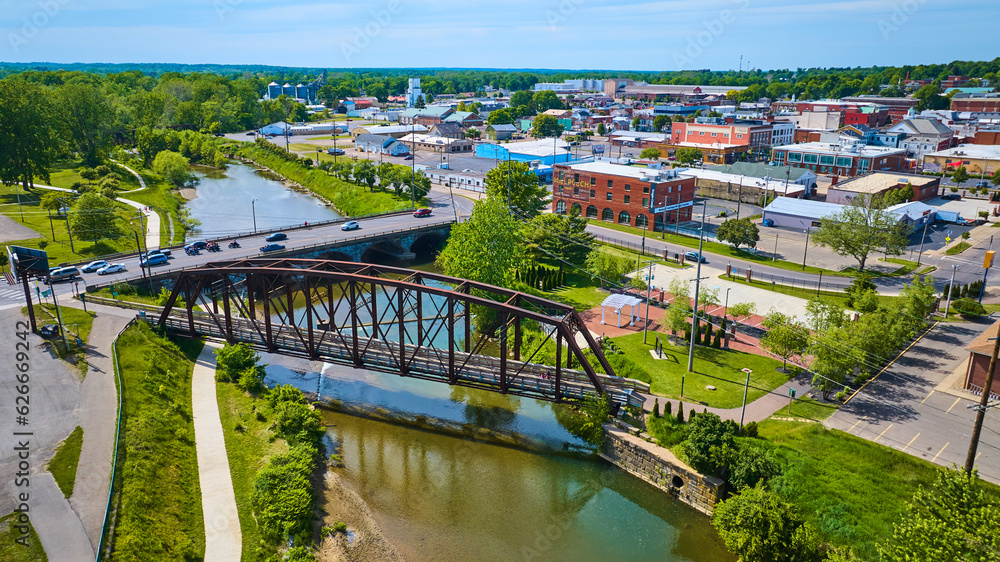 Vehicles crossing bridge over river with metal walking bridge and view of Mount Vernon Ohio aerial