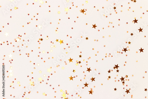 Glowing gold colored stars and crystals confetti on a gray background. Festive concept. Selective focus.