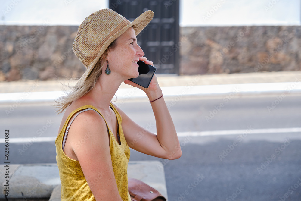 Smiling female talking on smartphone on summer street