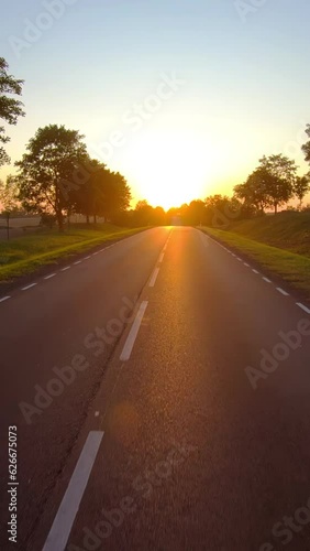 On a rural road to sunset, vertical pov