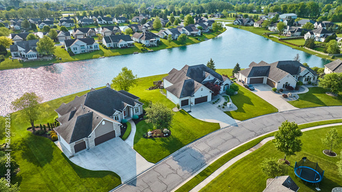 фотографія Large houses next to pond view and trampoline neighborhood aerial