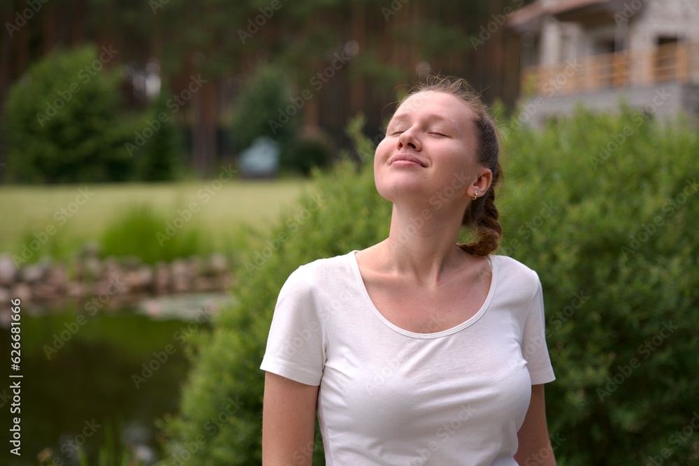 Portrait of happy young woman standing in the garden outside her luxury home and smiling and relax outside Portrait of happy young woman standing in the garden outside her luxury home and smiling and relax outside