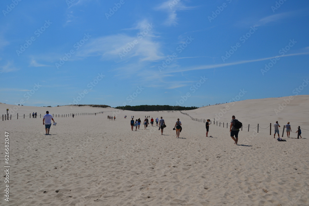 Moving dunes in the Slovincian National Park also known as Slowinski National Park. Tourists explore sand dunes by the Baltic Sea, Leba. Poland