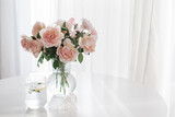 An elegant bouquet of fresh roses and placed by a light-filled window.