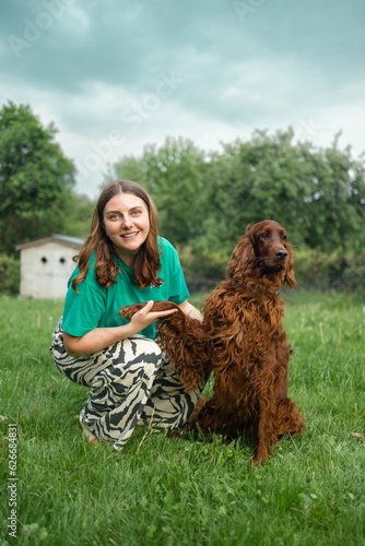Caucasian woman hugging Irish Setter dog pet cute adorable red dog friendly closeup closing eyes funny animals. Love and friendship between dog and owner in park. Outdoor training