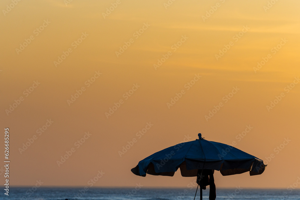 Blue umbrella in a sunset in front of the sea.