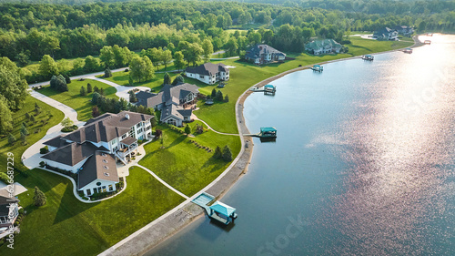 Fototapeta Naklejka Na Ścianę i Meble -  Sun glinting off lake with docks in water mansion lakeside properties with forest
