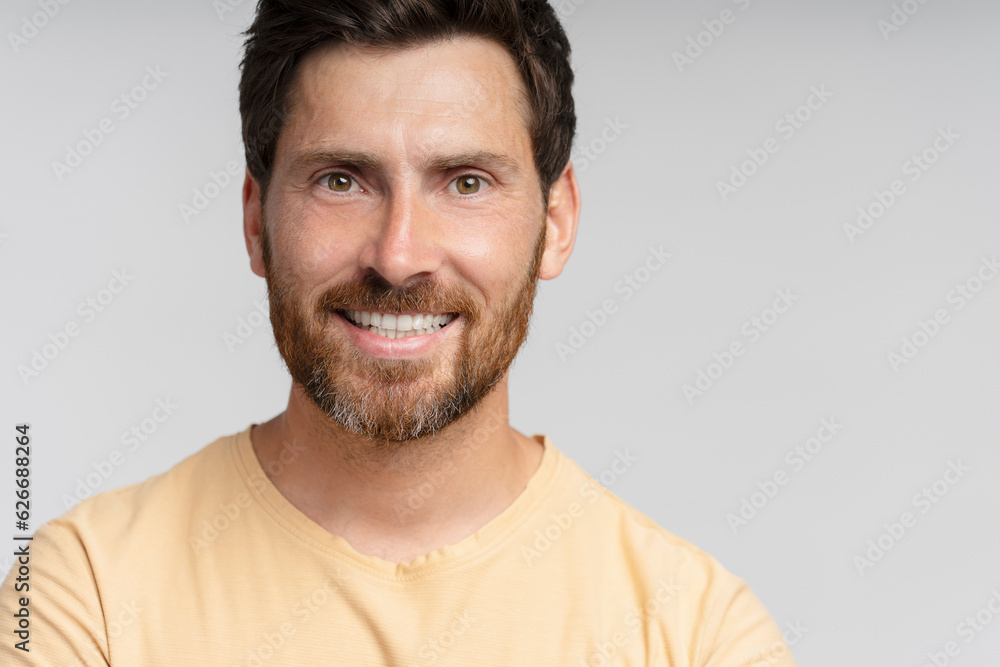 Fototapeta premium Portrait of middle aged smiling bearded man looking at camera isolated on gray background. Confident modern hipster with stylish hair after barbershop service
