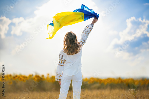Happy ukrainian woman with national flag on summer sky background. photo