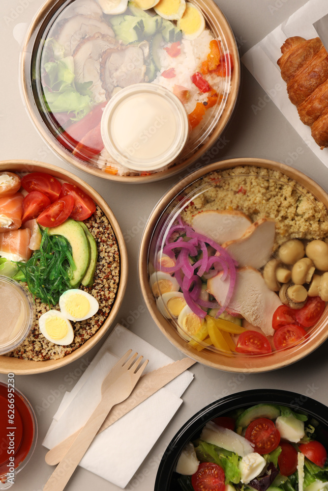 Tasty food in containers with wooden knife and fork on light grey table, flat lay Tasty food in containers with wooden knife and fork on light grey table, flat lay