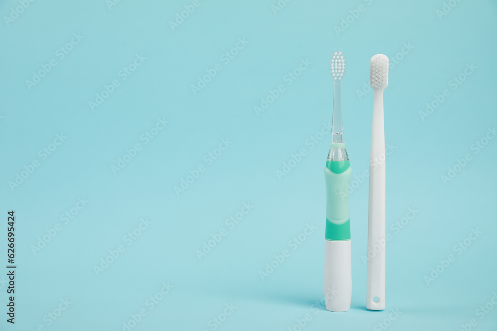 Electric and plastic toothbrushes on light blue background, space for text Electric and plastic toothbrushes on light blue background, space for text