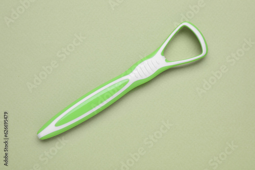 Green tongue cleaner on olive background  top view