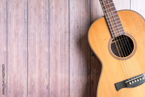 Acoustic guitar resting on rustic wooden background. Copy space.